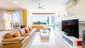 A living room with a sofa, TV, and a ceiling fan. - Villa 'Can Martinez' with Private Pool, Wi-Fi and Air Conditioning (Llucmajor)