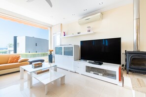 Ein modernes Wohnzimmer mit Flachbildfernseher, weißer Unterhaltungseinheit, Glastisch und Kamin.