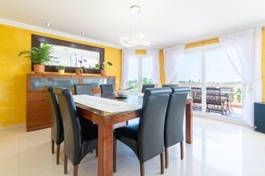 Un comedor con mesa de madera, sillas negras, una planta en maceta y vistas al exterior.