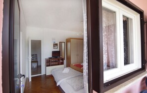 Ein Schlafzimmer mit Bett, Schreibtisch, Stuhl, Kleiderschrank und Fenster.