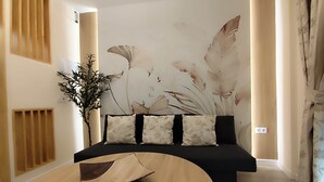 A modern living room with a black sofa, a wooden coffee table, a large wall mural, and a potted plant. - Albatros center Lucena (Lucena)