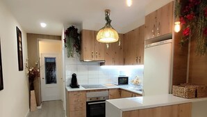 A modern kitchen with wooden cabinets, a central island, and hanging plants. - Albatros center Lucena (Lucena)