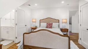 A bedroom with a bed, bedside tables, a nightstand, a mirror, and a door. - Warren House 2BR, Stunning Water Views Downtown (Plymouth)