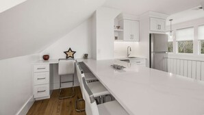 Una cocina moderna con armarios blancos, un refrigerador de acero inoxidable y una isla de encimera larga.
