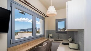 A kitchen with a view, a wooden counter, two chairs, a sink, and a toaster. - Harites Home – Sea View Villa A | Peaceful Island Escape with Stunning Views (Milos)