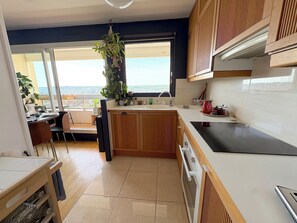 Une cuisine moderne avec des meubles en bois, un plan de travail noir et une fenêtre donnant sur un paysage urbain.