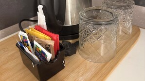 A kitchen with a kettle, a cutting board with food packaging, and two glass tumblers.