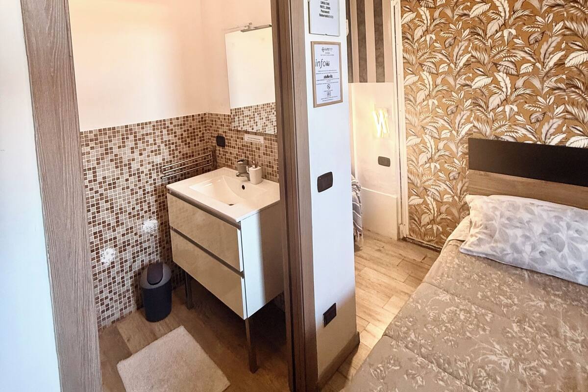 Une chambre d’hôtel avec une salle de bain, un lit, un miroir et une porte.
