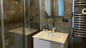 A bathroom with a glass-enclosed shower, a white sink with chrome fixtures, and a towel rack.