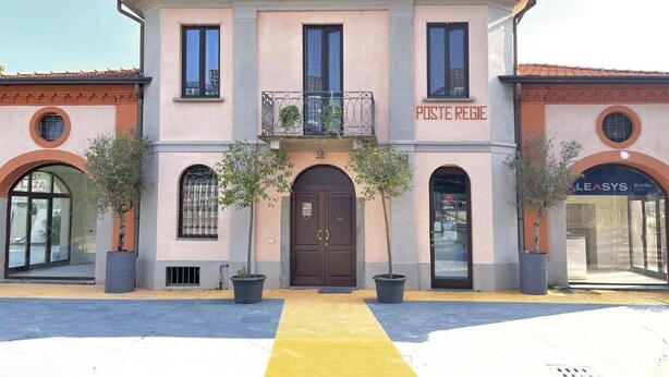 A building with a central entrance, a balcony, and a sign reading 'POSTE REGIE'.