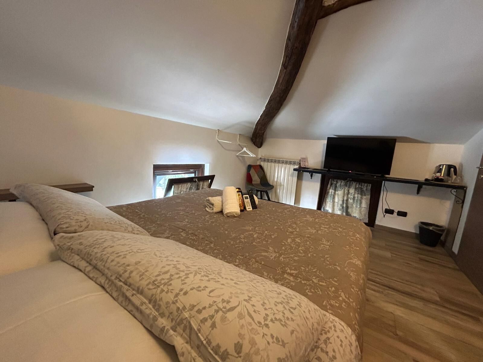 A bedroom with a large bed, a television, and a kitchenette area.