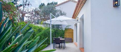 Un patio con una mesa, sillas, un paraguas blanco y una valla de madera.