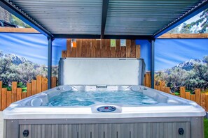 Ein Whirlpool mit Bedienfeld, umgeben von einem Holzzaun und einem Metalldach.