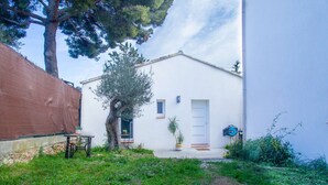 A white building with a door, windows, and a small garden area with plants and a tree. - Villa Provence -Clim-Terrasse-Jacuzzi®-BBQ (La Valette-du-Var)