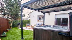 A backyard with a hot tub, a barbecue grill, and a covered patio area. - Villa Provence -Clim-Terrasse-Jacuzzi®-BBQ (La Valette-du-Var)