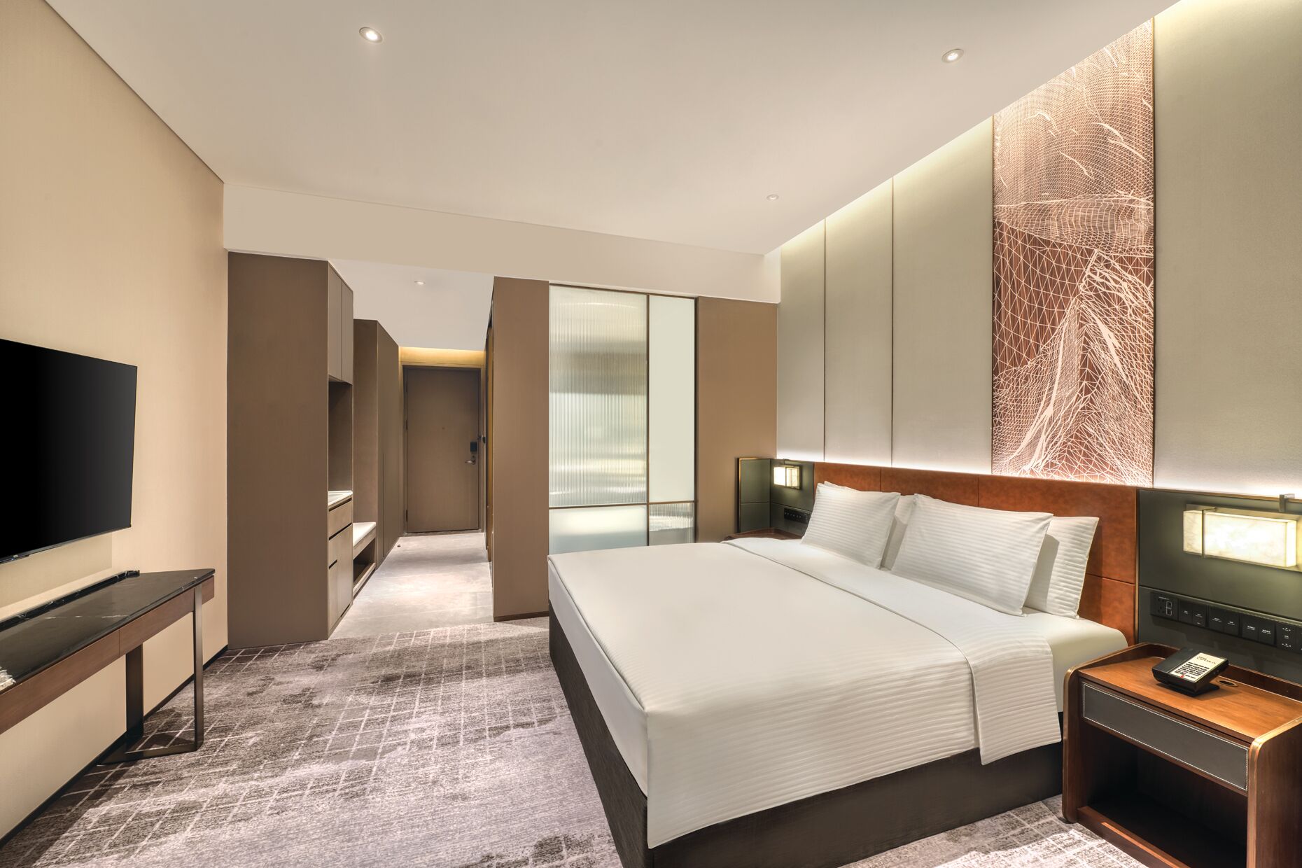 Een moderne hotelkamer met een groot bed, een televisie, een bureau en een inloopkast.