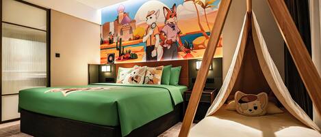 A hotel room with a large mural, a bed with green bedding, a tent-like structure, and a plush toy on the bed.