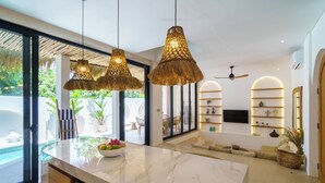 A modern kitchen with a marble countertop, hanging wicker chandeliers, and a view of the outdoor area. - Stunning 4 BR villa with rooftop - 3 min from Balangan beach (Badung)