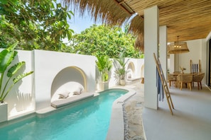 Un espace piscine au design incurvé, avec des murs blancs et des plantes en pot.
