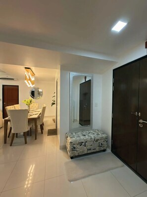 A modern living room with a dining area, a large wardrobe, and a mirror. - 3BR Apartment with Balcony at One Uptown BGC (Taguig)