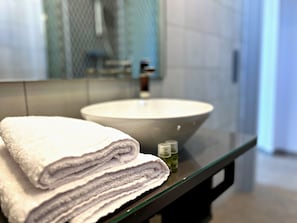 Ein Badezimmer mit einem großen Waschbecken, einem Spiegel und gestapelten Handtüchern.