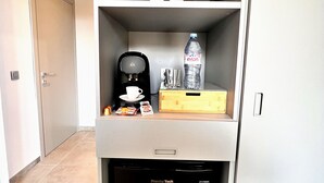 A compact kitchenette with a coffee maker, a water bottle, and a box of snacks. - Appartement 10B - MyResidenced'Azur (Beausoleil)