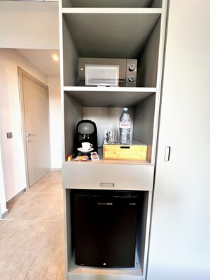 Eine kleine Küchenzeile mit Kaffeemaschine, einer Wasserflasche und einer Tüte Snacks.