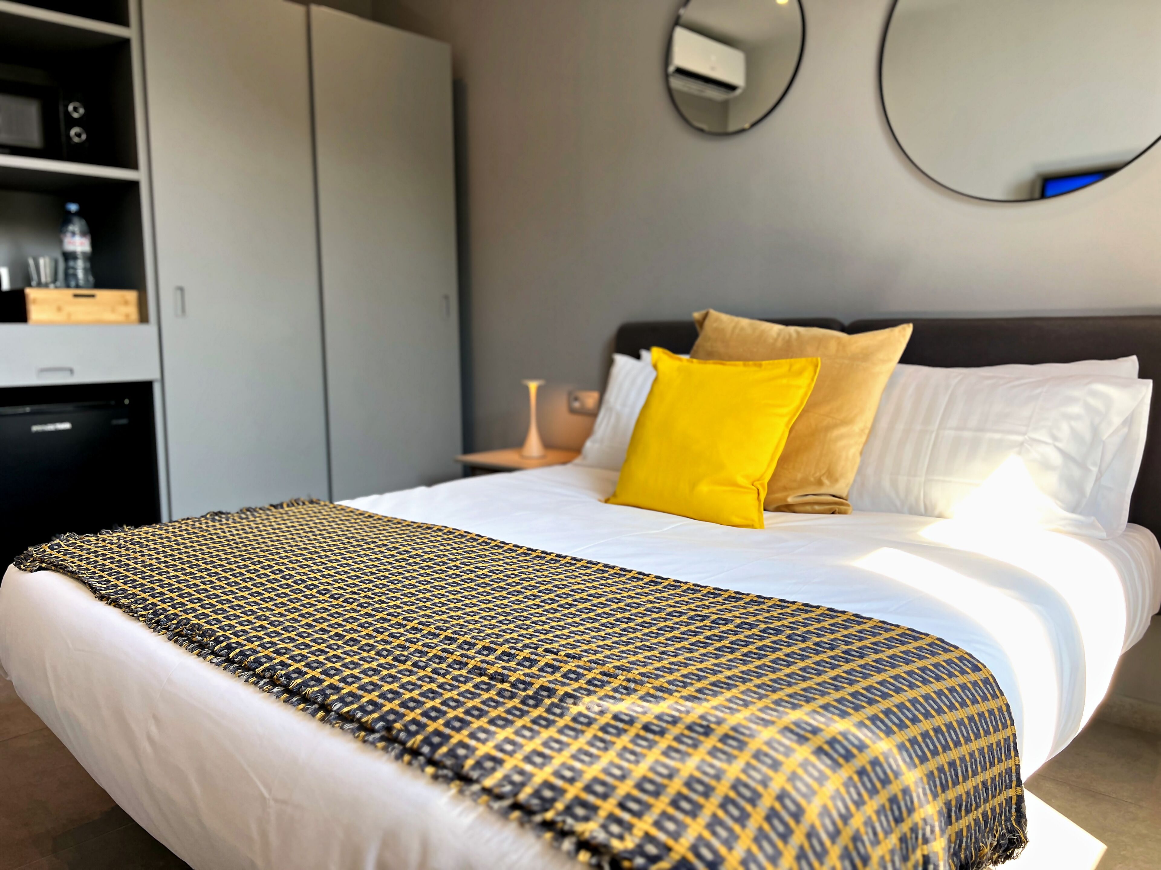 Een hotelkamer met een bed, een kledingkast, een spiegel en een nachtkastje.