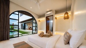 Ein modernes Schlafzimmer mit großem Bett, Blick auf einen Pool und einer offenen Raumgestaltung.