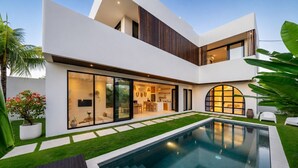 Ein modernes, zweistöckiges Haus mit Swimmingpool, gepflegtem Rasen und einer Terrassenfläche.