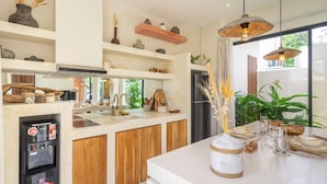 Una cocina moderna con armarios de madera, una cafetera integrada y un amplio ventanal con vistas a zonas verdes.
