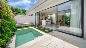 Una casa moderna con piscina, un porche acristalado y jardín.