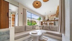 Una sala de estar moderna con un sofá modular, una mesa redonda y un comedor con una mesa y sillas de madera.