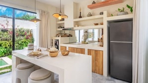 Una cocina moderna con una isla central, armarios de madera y un refrigerador de acero inoxidable.