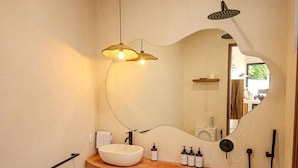 Une salle de bain avec un meuble-lavabo en bois, un lavabo rond, un miroir et une douche.