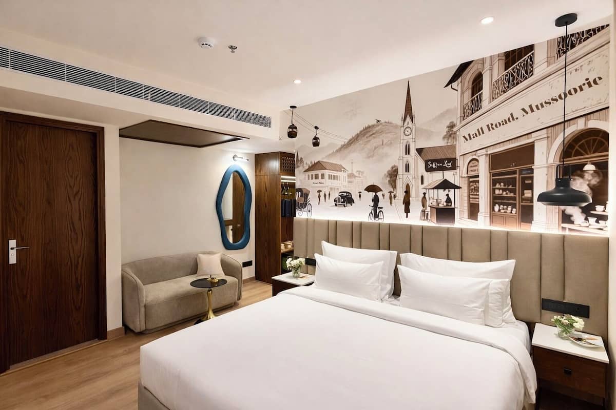A modern hotel room with a large bed, a sofa, a mirror, and a mural of a street scene.