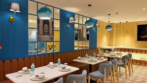 A restaurant with blue paneled walls, multiple dining tables, and booths.