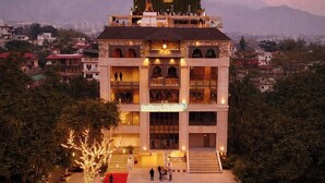 A multi-story hotel with a central atrium, balconies, and a red carpet leading to the entrance.