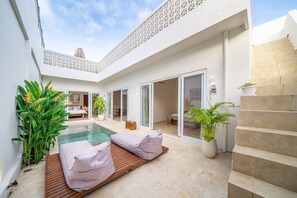 A modern villa with a swimming pool, a wooden deck, a staircase, and a large open living area. - 2BR Nunggalan Villa with Pool & Rooftop (South Kuta)