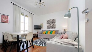 Ein modernes Wohnzimmer mit Esstisch, Sofa und Fernseher.