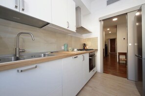 A modern kitchen with white cabinets, stainless steel appliances, and a wooden countertop. - Monteverde - Large and comfortable apartment for 8 (Roma)