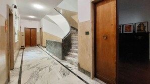 Ein Korridor mit Marmorboden, einer Holztür und einer Treppe.