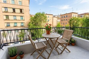A balcony with two wooden chairs and a round table, potted plants, and a view of surrounding buildings. - Monteverde - Large and comfortable apartment for 8 (Roma)