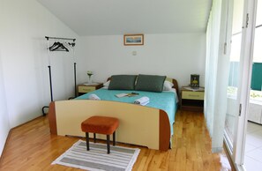 A bedroom with a bed, a bench, a bedside table, a hanging clothes rack, and a window. - Prime Location Apartment Nicely Equipped (Umag)