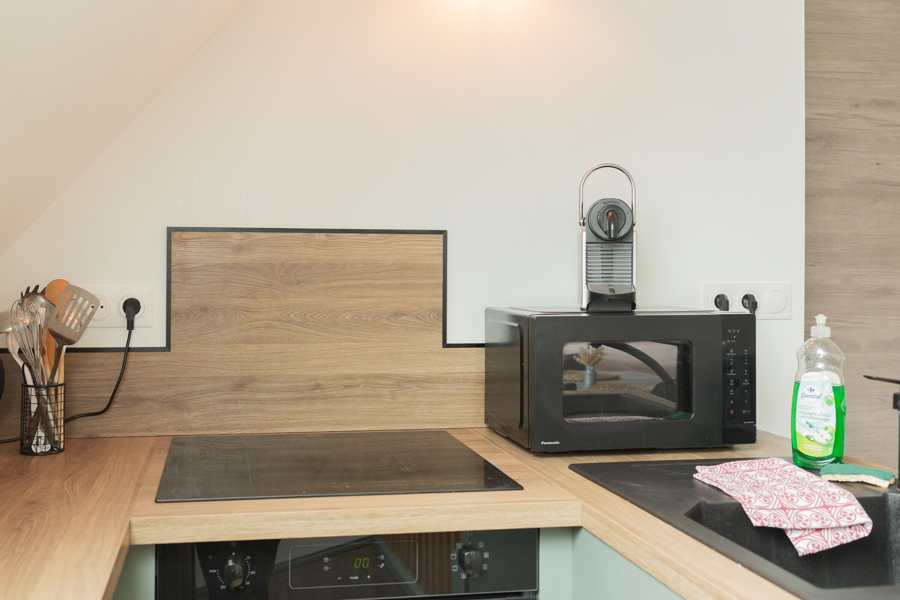 A kitchen with a microwave, a built-in oven, and a wooden countertop.