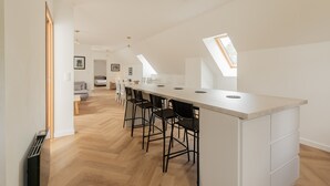 Eine moderne Küche mit einer langen Kochinsel, schwarzen Barhocker und Oberlichtern.