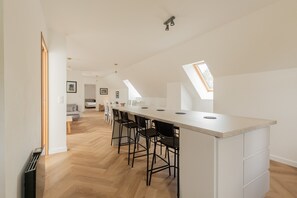 Una cucina moderna con un'isola lunga, sgabelli da bar neri e lucernari.