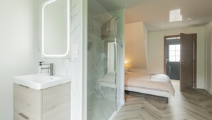 Ein modernes Badezimmer mit Duschkabine aus Glas, einem weißen Waschbecken und einer Marmor-Spritzschutzwand.