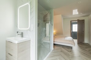 Un bagno moderno con box doccia in vetro, lavandino bianco e schienale in marmo.