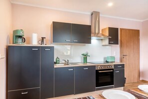 Una cocina moderna con armarios oscuros, una campana extractora de acero inoxidable y un horno empotrado.
